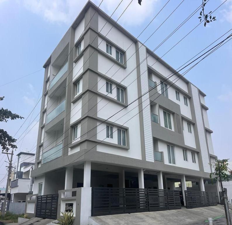 a tall white building withwindows at Thulasi Avenue Inn in Pollāchi