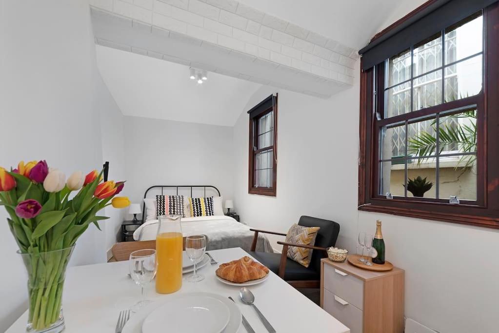 a white room with a table with a vase of flowers at Cosy Little Venice Pied-à-Terre by MoreThanStays in London