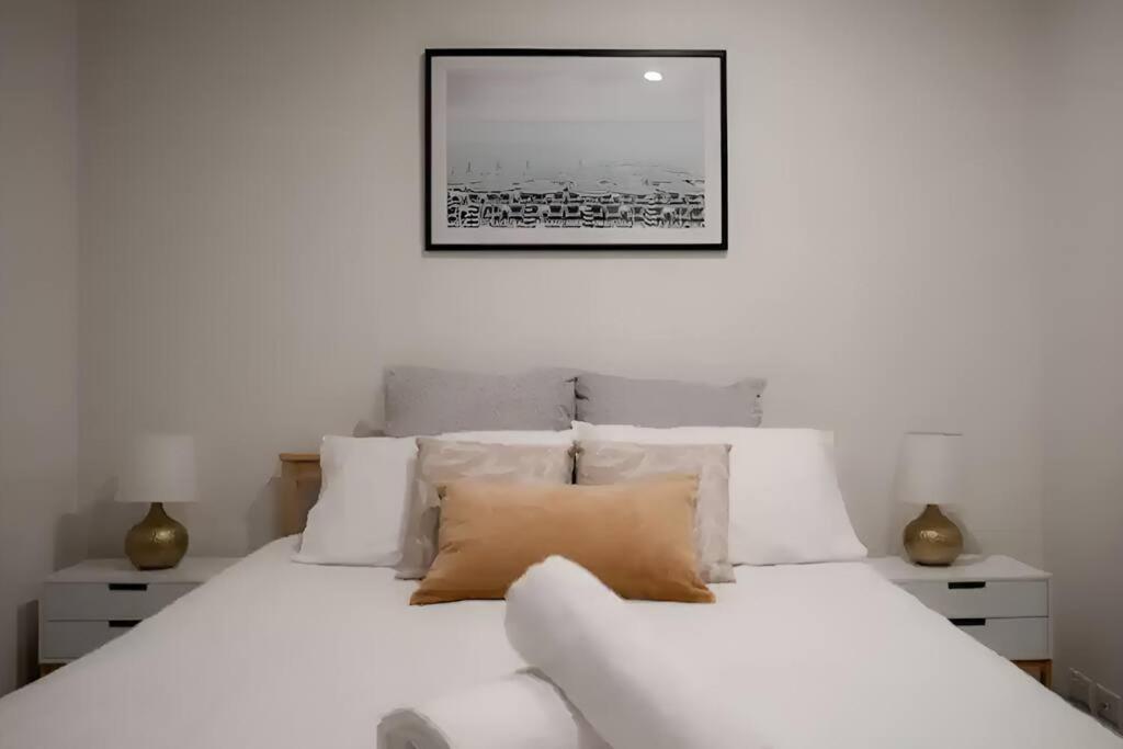 メルボルンにあるMt1012 - 1 BR Docklands Delight, Stunning Apartmentの白い枕と壁に絵が描かれた白いベッド