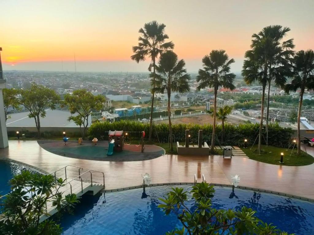 a resort with two pools and palm trees and a sunset at Tanglin Orchard Apartment (2BR) in Surabaya