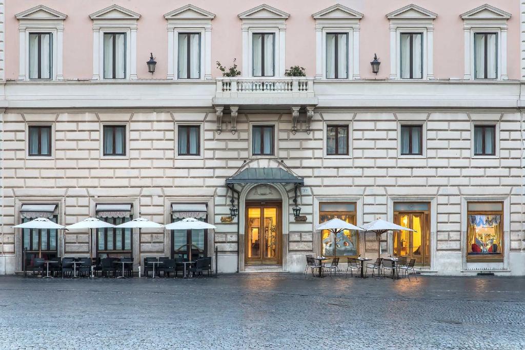 a building with tables and umbrellas in front of it at Albergo del Senato in Rome