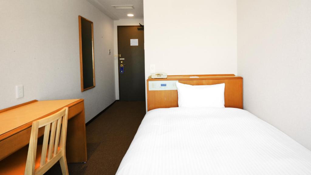 a small room with a bed and a desk at Smile Hotel Sugamo in Tokyo