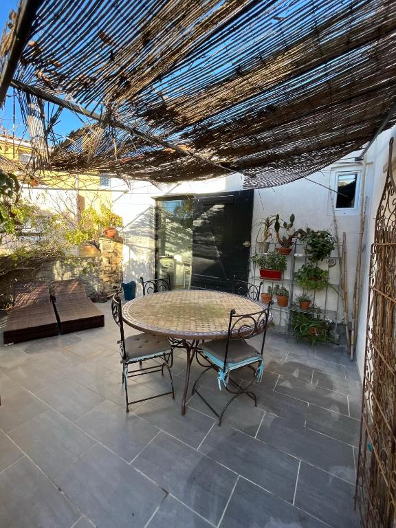 un patio avec une table et des chaises sur un patio dans l'établissement La Dépendance 13D rue Pasteur, à Saint-Mandrier-sur-Mer