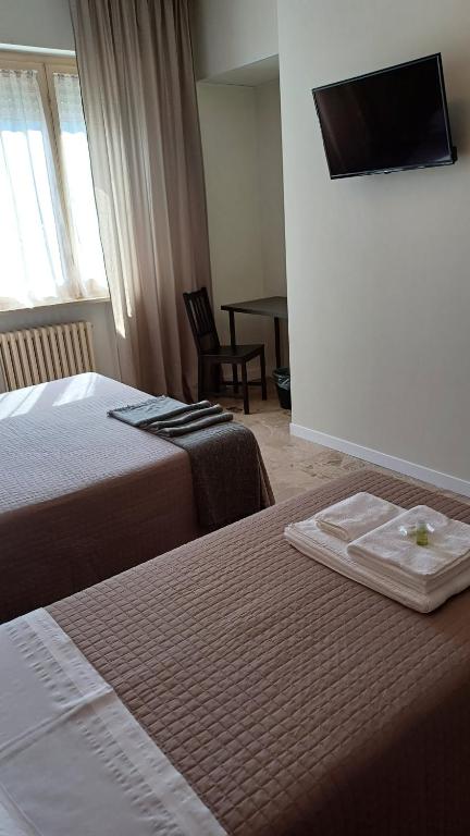 a hotel room with two beds and a tv on the wall at B&B Monté in Montesilvano