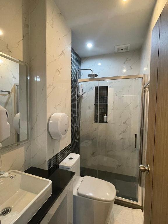 A narrow modern bathroom with a glass-enclosed shower.
