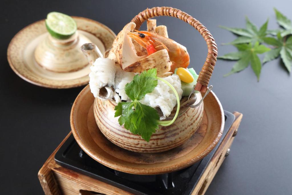 a bowl of food on a plate on a table at Hotel Binario Saga Arashiyama in Kyoto