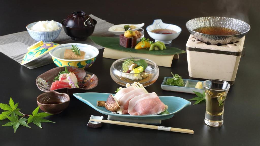 a table topped with plates of food and chopsticks at Hotel Binario Saga Arashiyama in Kyoto