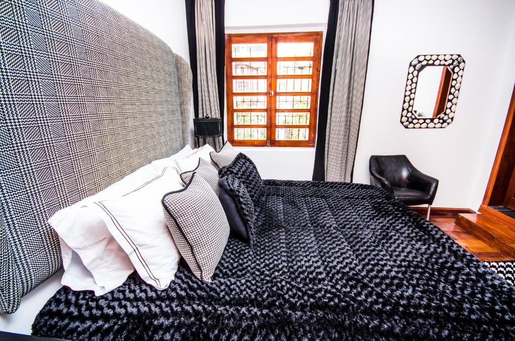 a bedroom with a bed with a headboard and a chair at Hotel + Arte in Quito