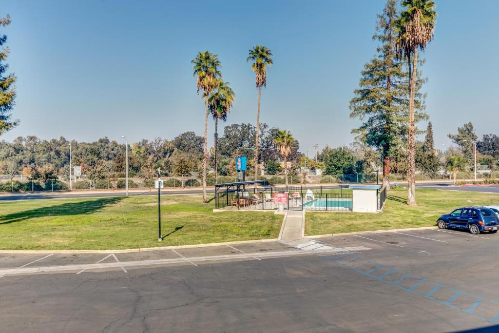 a parking lot with a basketball hoop and palm trees at Motel 6-Visalia, CA in Visalia