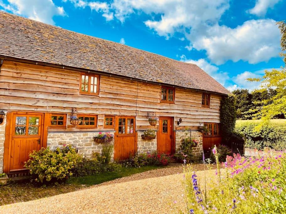 LeintwardineにあるTawny Owl Barnの木製のドアと花のある木造の家
