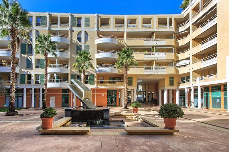 un grand bâtiment avec des palmiers devant dans l'établissement Port Nicea Residence, à Nice