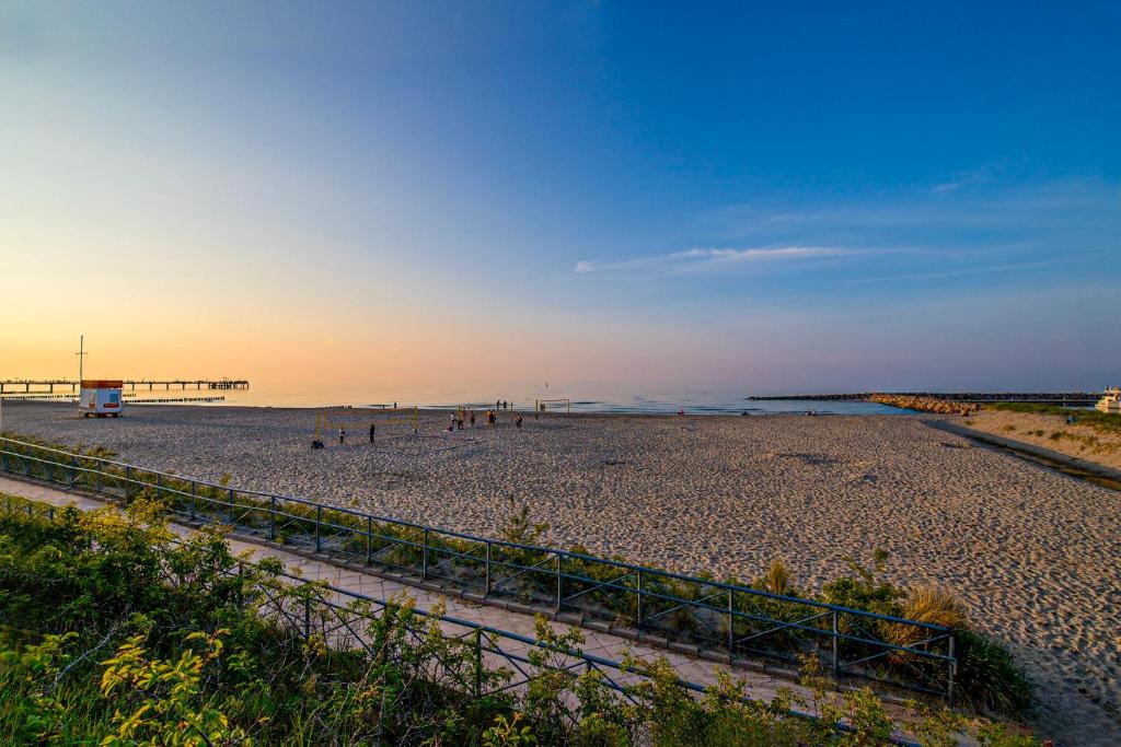 a beach with a pier and people on the beach at Morada Strandhotel Ostseebad Kühlungsborn in Kühlungsborn