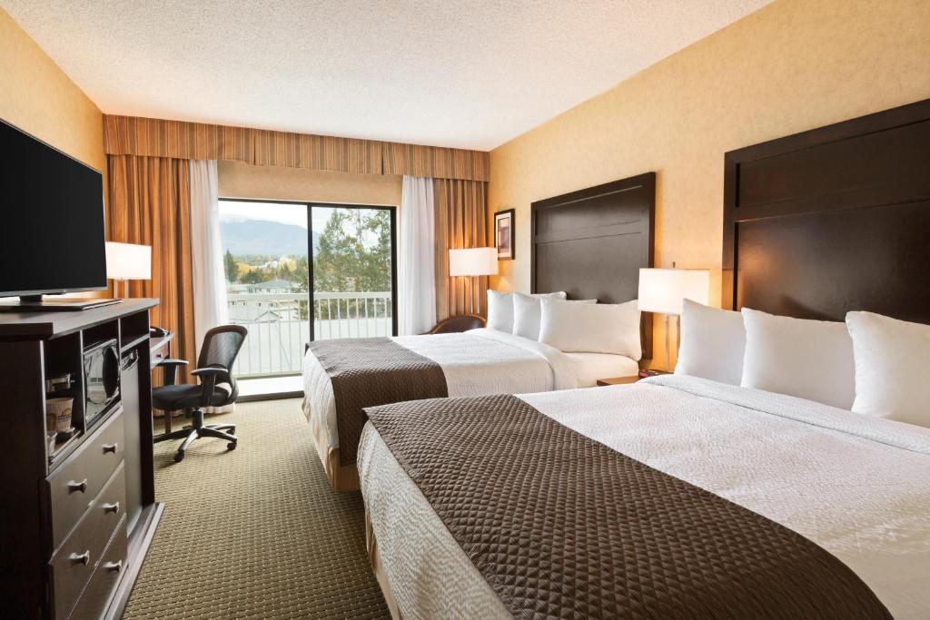 um quarto de hotel com duas camas e uma televisão em Days Inn by Wyndham Cranbrook Conference Centre em Cranbrook