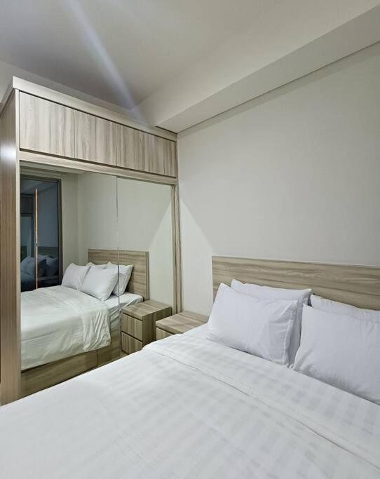 ジャカルタにあるGold Coast USA Room Studio netflixのベッドが2つと鏡があるホテルの部屋