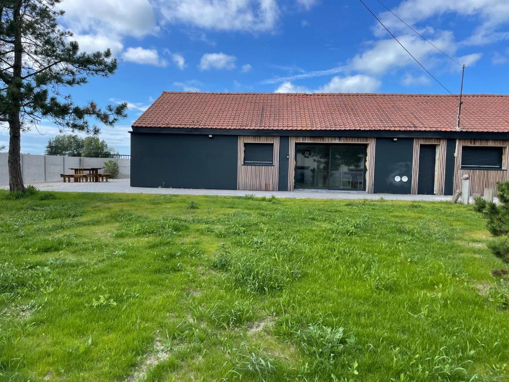 une maison avec une cour verdoyante devant elle dans l'établissement la Bigoudène pour 8 personnes, à Les Hemmes de Marck