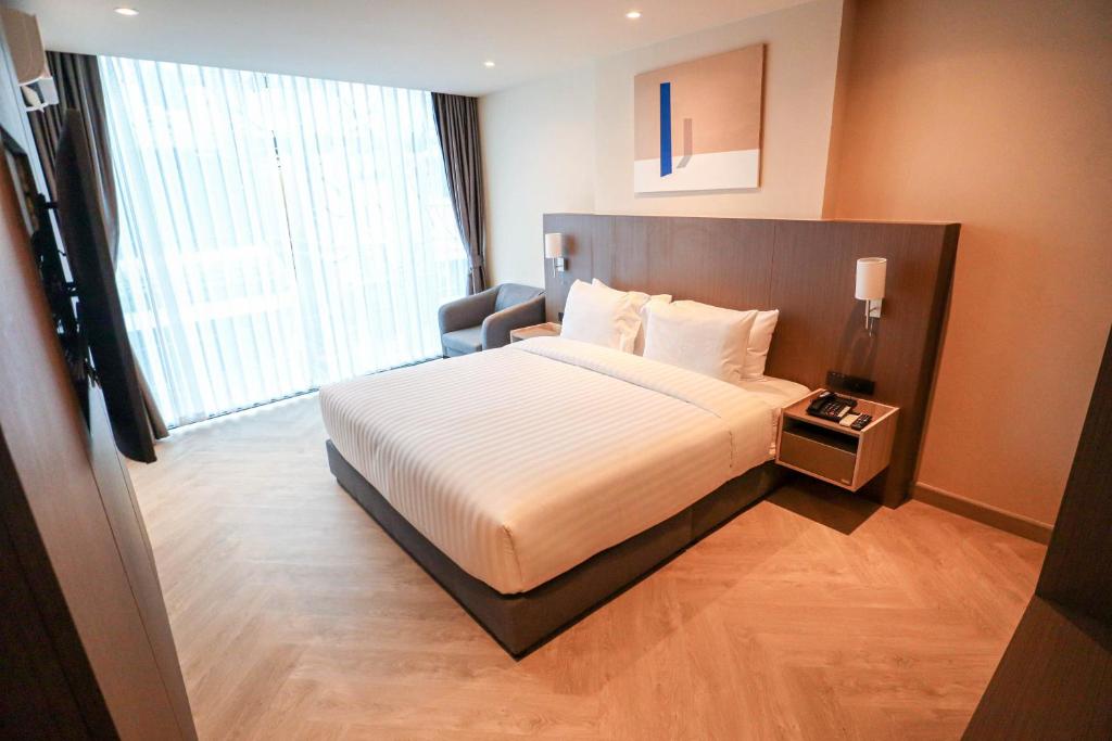 a hotel room with a bed and a large window at The One Cozy Living in Pattaya