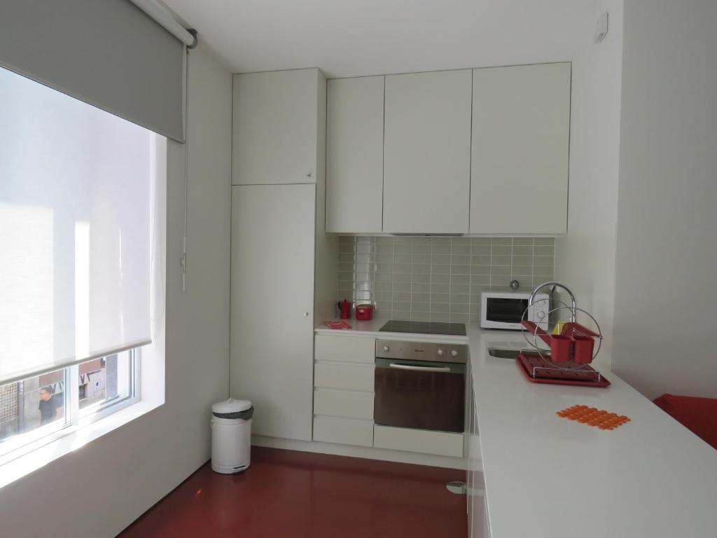cocina con armarios blancos y encimera blanca en Miguel Bombarda - Porto Houses & Suites, en Oporto