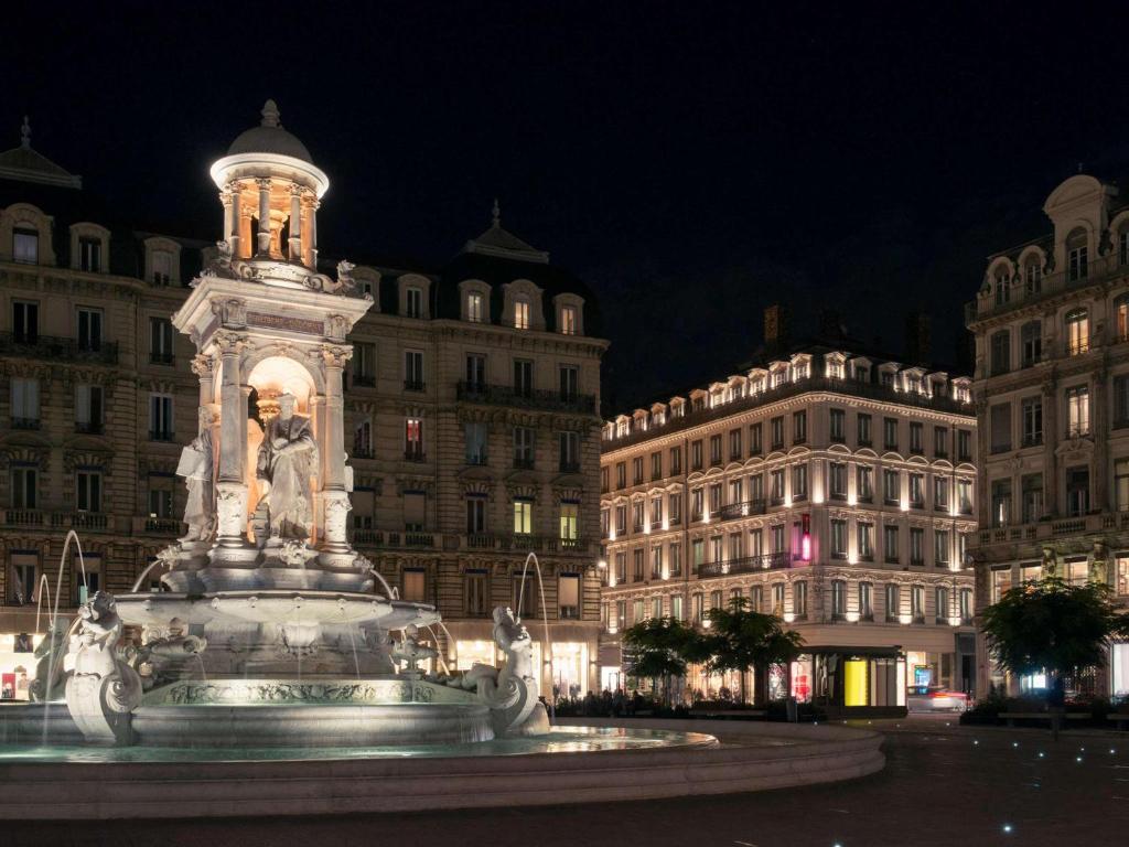 a fountain in the middle of a city at night at Mercure Lyon Centre Beaux-Arts in Lyon