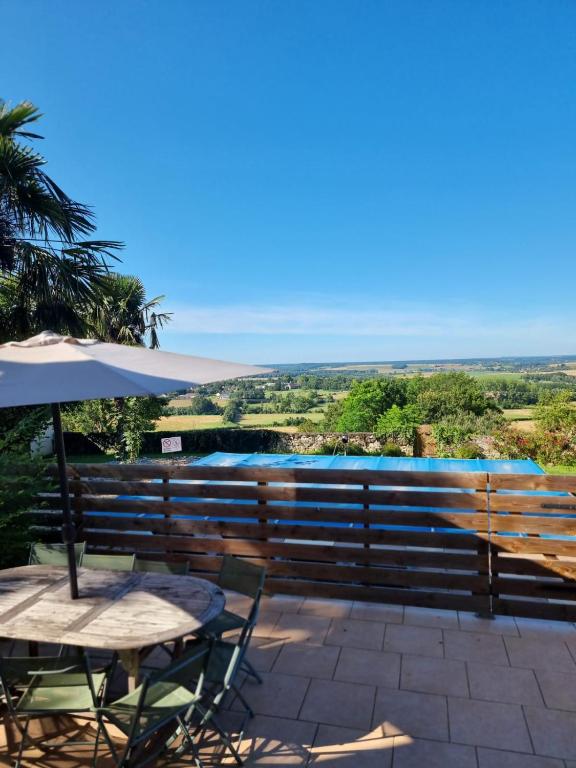 un patio avec une table et un parasol dans l'établissement Maison chaleureuse avec vue exceptionnelle, à Chaulgnes
