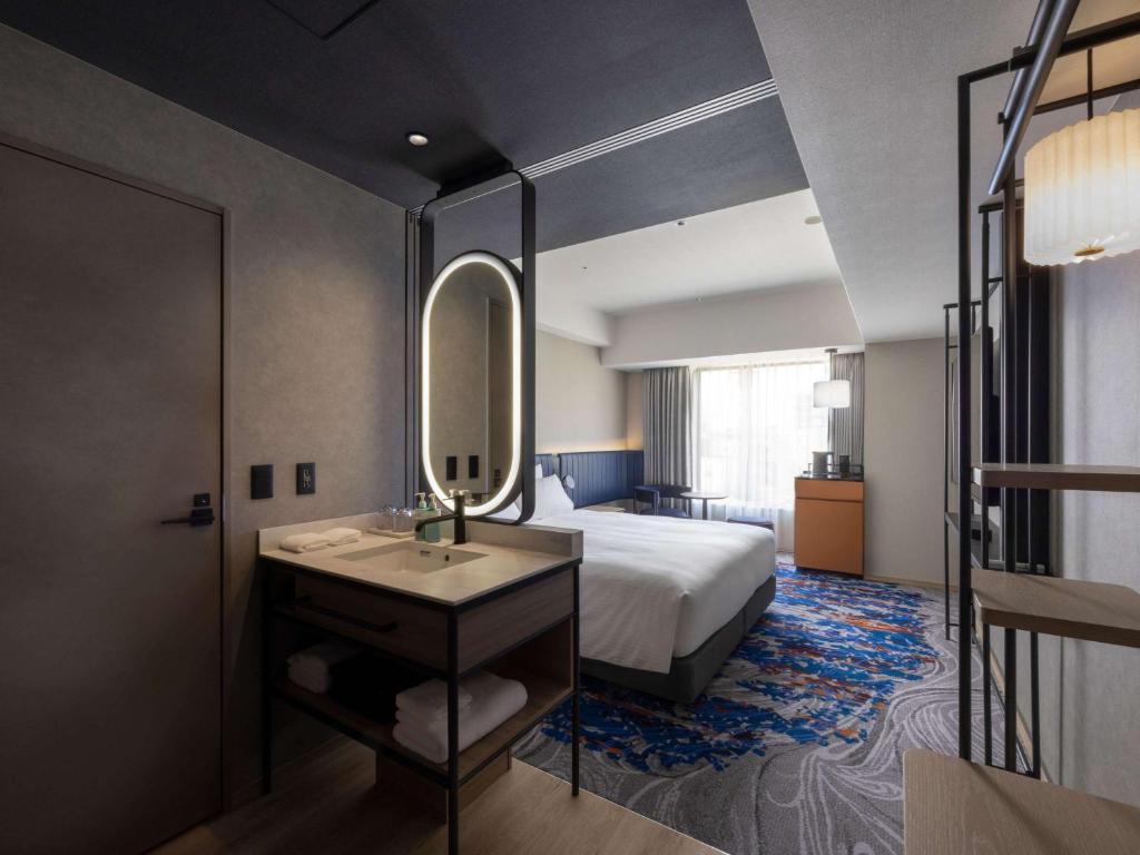 a bedroom with a bed and a sink and a mirror at Novotel Nara in Nara