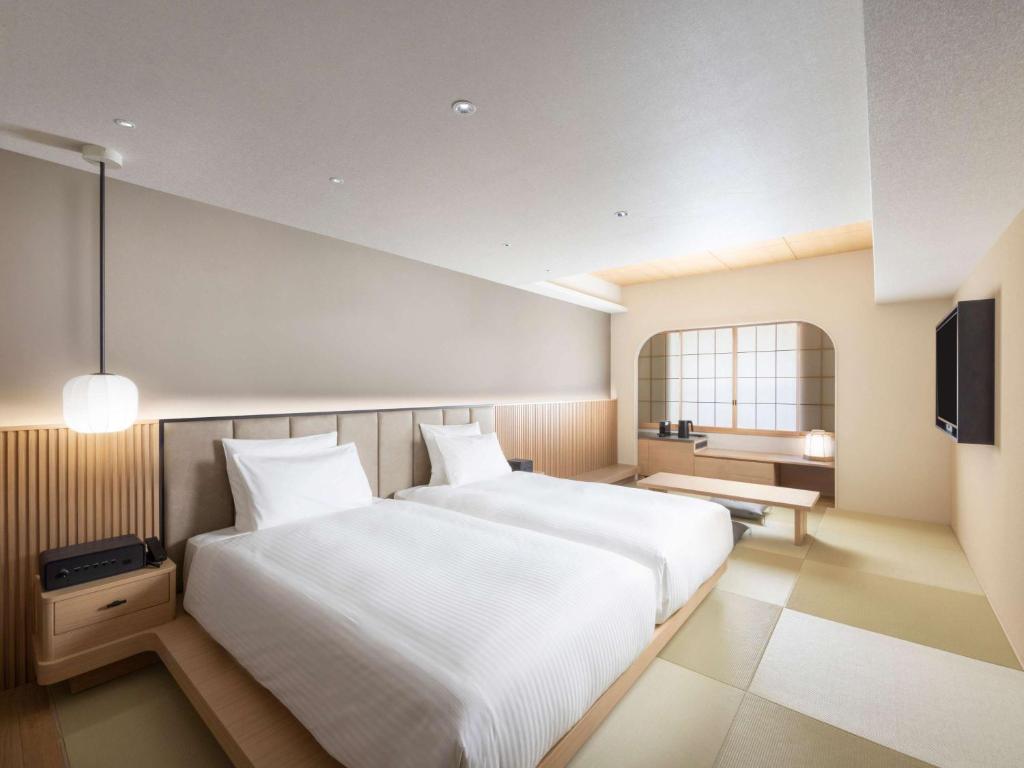 a bedroom with a large white bed and a television at Novotel Nara in Nara