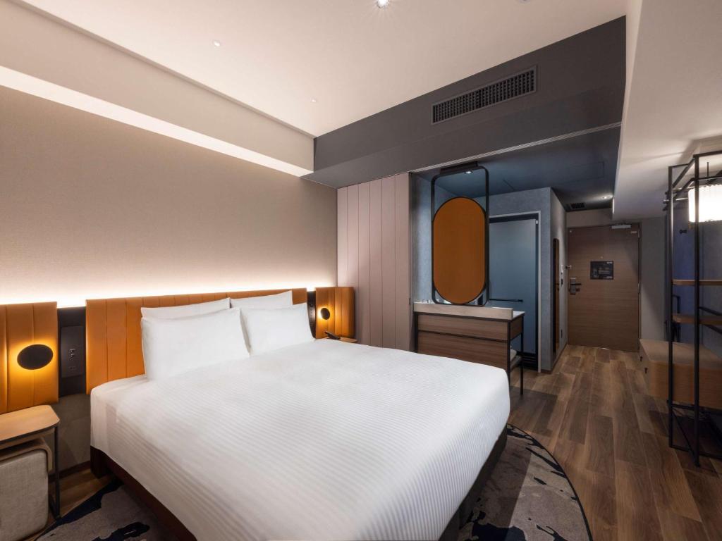 a bedroom with a large white bed and a mirror at Novotel Nara in Nara