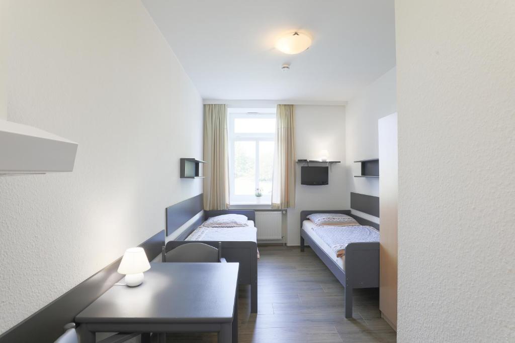 ハンブルクにあるBerne Apartmentsのベッド2台とテーブルがある小さな部屋