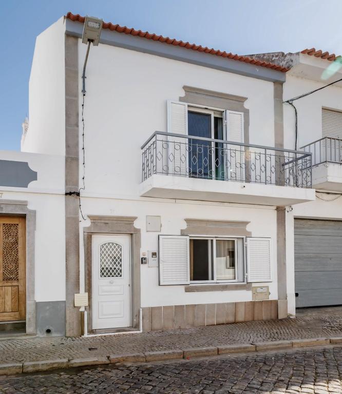 a white house with a balcony and a door at Casa Delgado in Tavira