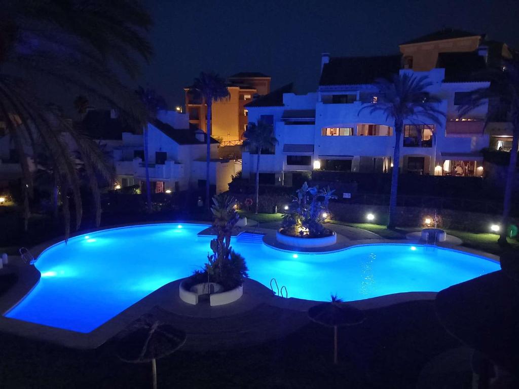 Una gran piscina azul por la noche con edificios. en Islantilla Beach Golf, en Islantilla