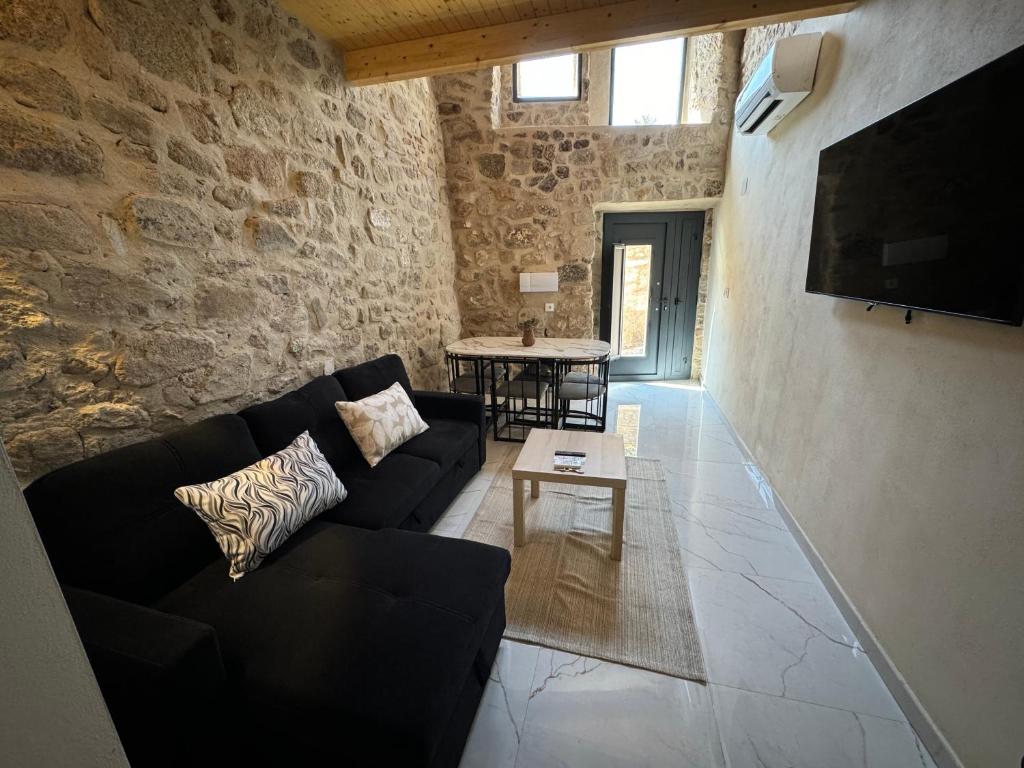 a living room with a black couch and a tv at La Villa Suites, Mirador de Alhamar in Trujillo