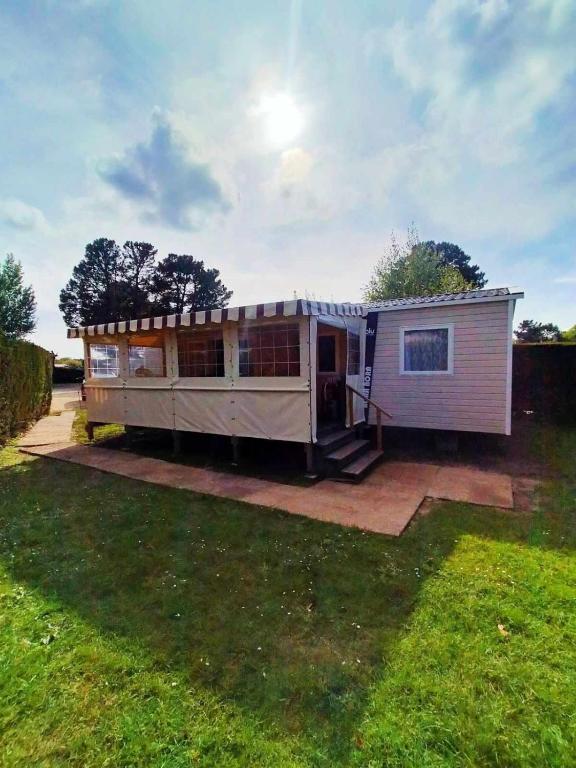 Une petite maison est assise dans une cour dans l'établissement La Palmyre - Les Mathes - Mobil home 3 ch LUXUEUX de 40m2 - Grand emplacement dans village loisirs 4 étoiles - 