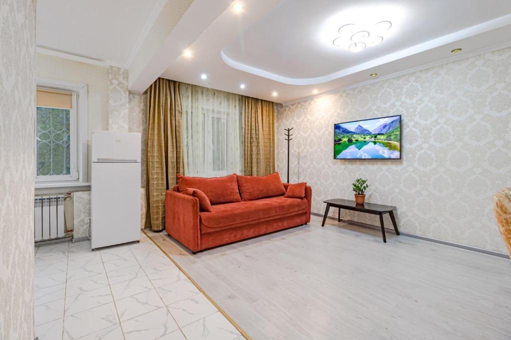 ein Wohnzimmer mit einem roten Sofa und einem Kühlschrank in der Unterkunft Трехкомнатная квартира рядом с ЖД вокзалом in Pawlodar