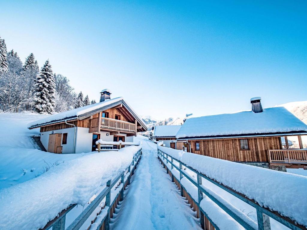 a building with snow on the ground next to a fence at Chalet 3* Valmorel, skis aux pieds, 3 chambres, parking, WIFI - FR-1-356-401 in Valmorel