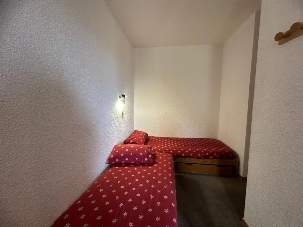Cette petite chambre comprend un petit lit avec des draps rouges. dans l'établissement Studio Divisible Fonctionnel · Accès Direct Pistes · Balcon · 4 Pers - FR-1-181-2242, à La Plagne Tarentaise