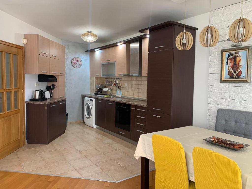 a kitchen with a table and yellow chairs at Asinela Home с гараж in Burgas City