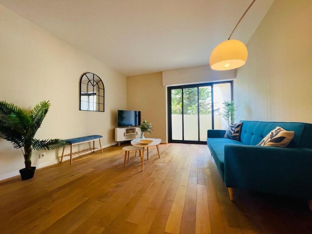 een woonkamer met een blauwe bank en een tafel bij Casa du Haras in Angers