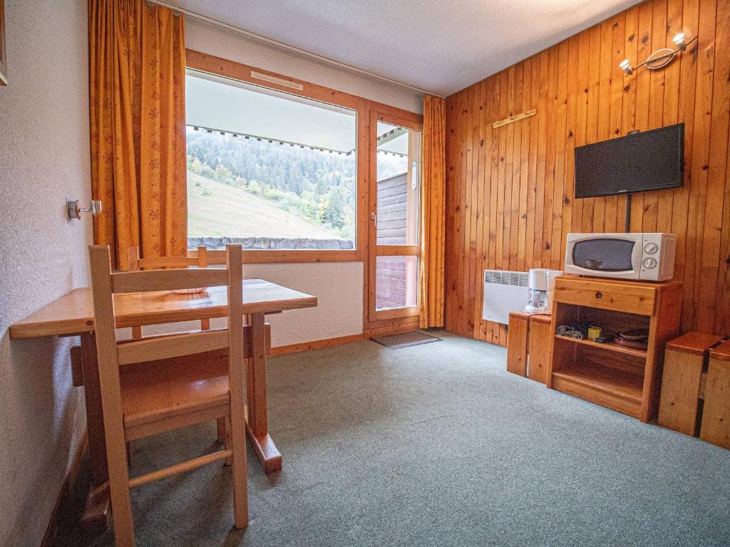 Cette chambre dispose d'une table, d'une télévision et d'une fenêtre. dans l'établissement Studio avec balcon pour 2 pers, départ skis aux pieds, proche piste et ESF - FR-1-356-215, à Valmorel