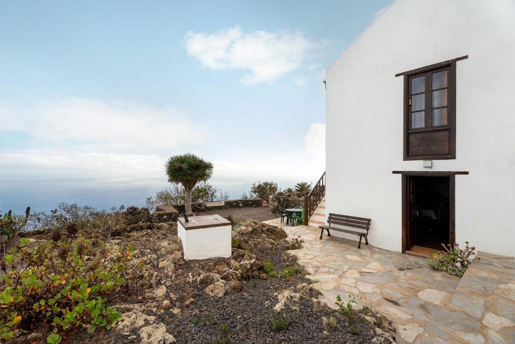 ein weißes Gebäude mit einer Bank und einem Baum in der Unterkunft Casa Rural La Era in Valverde