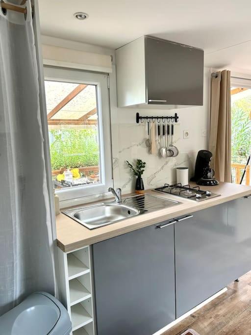 une petite cuisine avec un évier et une fenêtre dans l'établissement Mobil home à la tamarissière, au Grau-dʼAgde