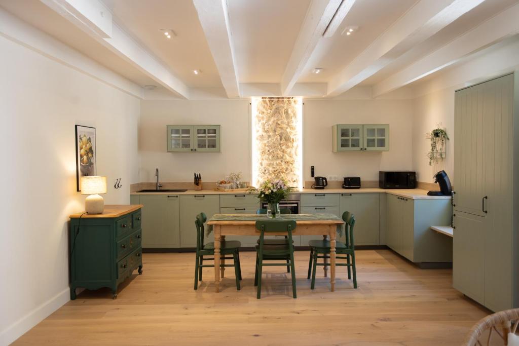 une cuisine avec des armoires vertes, une table et des chaises dans l'établissement Gites de Chateau Gasqui, à Gonfaron