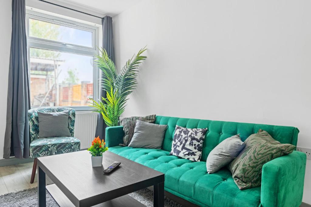 a green couch in a living room with a table at Stanion Luxurious 3 Bedroom Modern House Northamptonshire, Double, Twins, Single, Free Parking, Free Wi-Fi, Pets, Up to 8 Sleeps, 4 Smart TVs in Corby