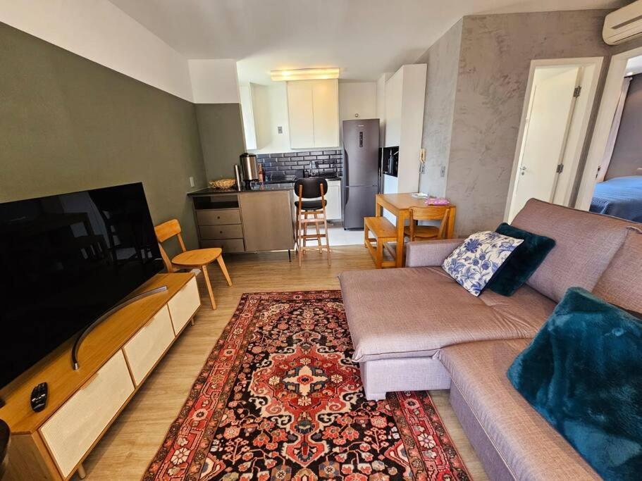 sala de estar con sofá y TV y cocina en Apto completo super confortável e moderno próximo Metro Vila Madalena, en São Paulo
