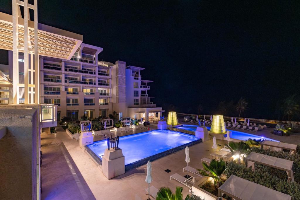 a swimming pool in front of a hotel at night at Wyndham Grand Barbados Sam Lords Castle All Inclusive Resort in Saint Philip