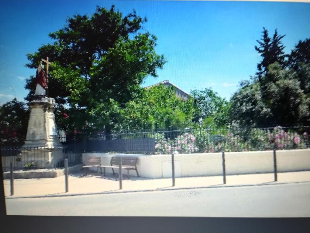 a statue and a bench in front of a fence at Entre mer et cevennes in Boisseron