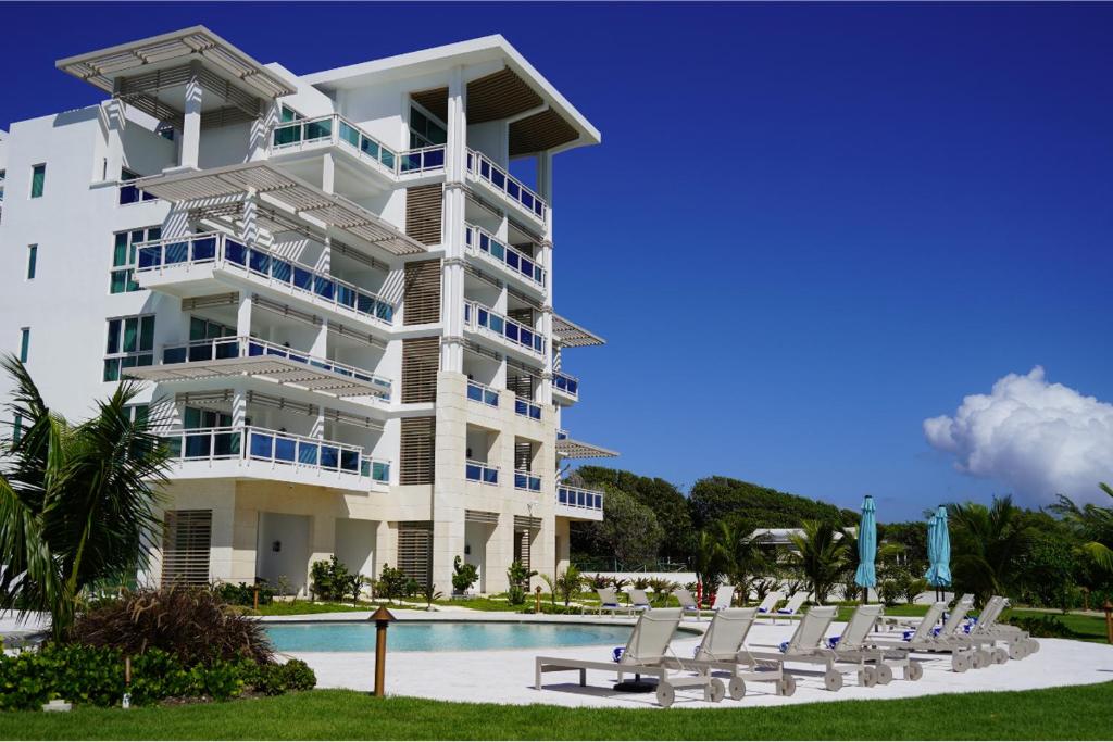 a large white building with lounge chairs next to a pool at Wyndham Grand Barbados Sam Lords Castle All Inclusive Resort in Saint Philip