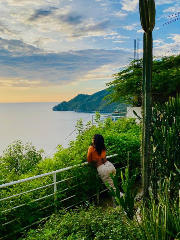 a woman sitting on a fence looking at the water at Sol y Luna apartment in Santa Marta