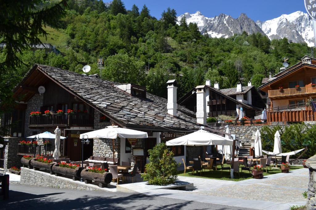 un edificio con tavoli e ombrelloni di fronte ad esso di Hotel Pilier D'Angle & Wellness a Courmayeur