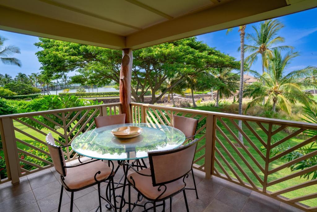 een balkon met een tafel en stoelen en palmbomen bij G22 Waikoloa Beach Villas in Waikoloa