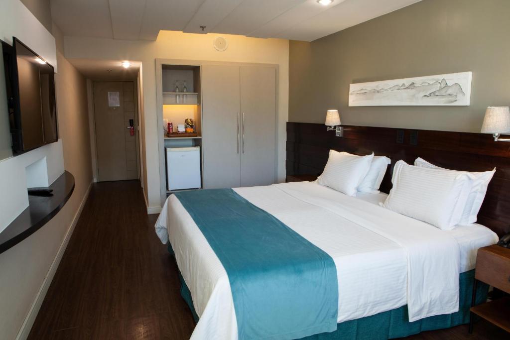 a hotel room with a large bed and a kitchen at Sol Ipanema Hotel in Rio de Janeiro