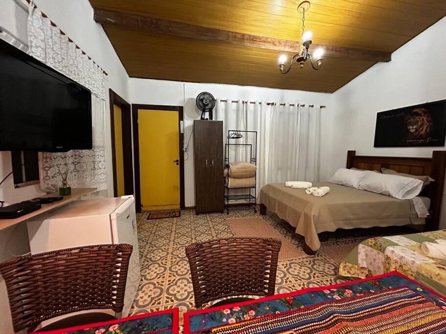 a bedroom with a bed and a tv and chairs at Casa na Estrada Real - Tiradentes in Tiradentes
